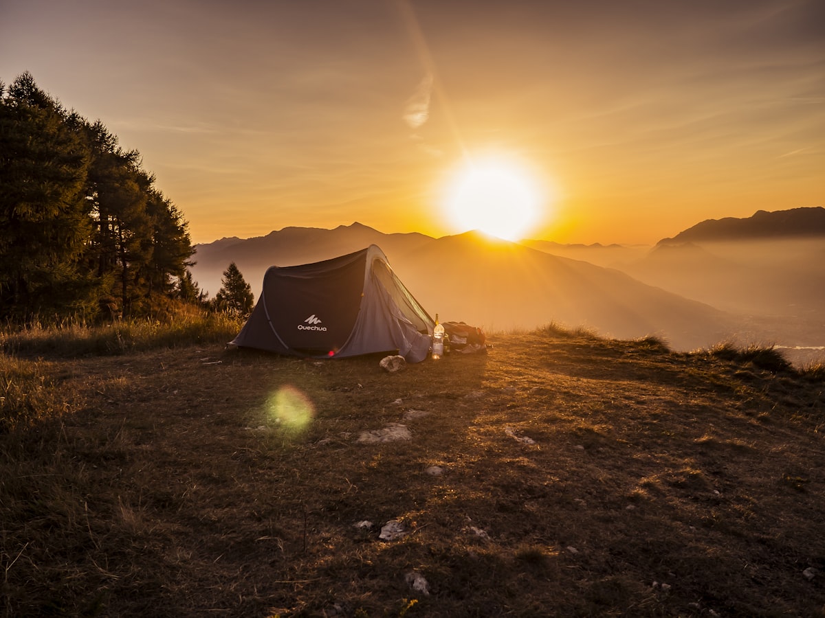 A dome tent silhouetted against bright sun on open high ground - solo camping for two desert camping