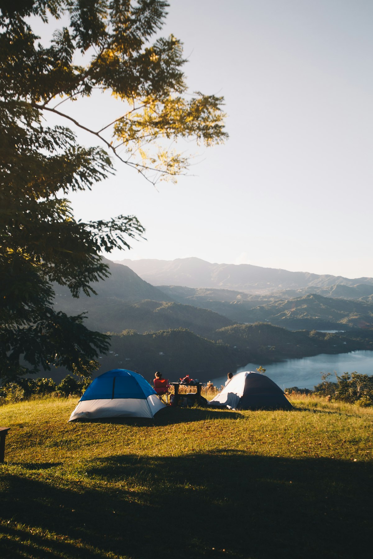 Two shelters set up near a lake in the trees - solo camping for two hammock camping setup