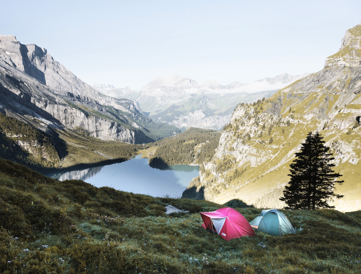 Two tents pitched on a grassy mountainside - solo camping for two trip planning